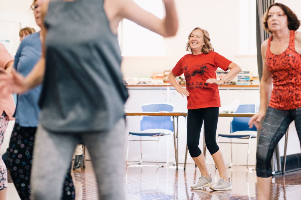 Older women dancing together, staying active and enjoying life during midlife and beyond.